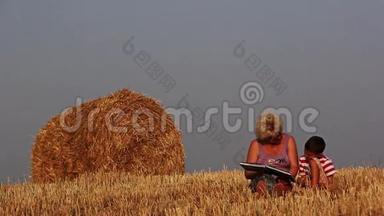 女人读一本书男孩，在田野里，妈妈读一本书给儿子